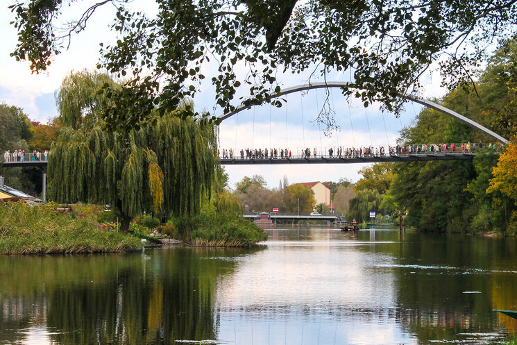 Seitenansicht Brücke über Wasser mit Menschen und umgeben von Bäumen